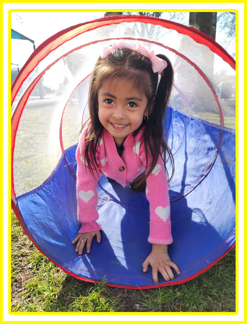 preschool girl crawling in play tube